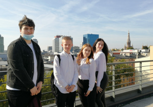 Czworo uczniów na tarasie widokowym hotelu, z tyłu panorama miasta